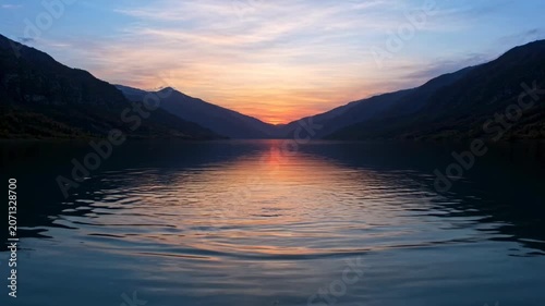 The images depict a serene body of water nestled between mountain ranges, capturing the peaceful moment of a sunset or sunrise