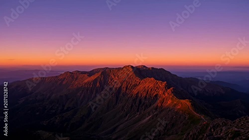 The video captures a scenic mountain landscape during the transition from sunset to twilight