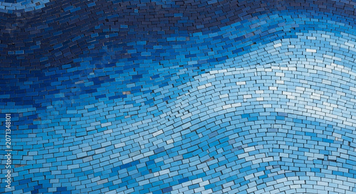 Wavy blue mosaic tile wall texture featuring a gradient of ceramic pieces from dark navy to light sky blue