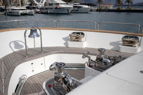 Anchor winches and a ship’s bell mounted at the bow of a luxury motor yacht