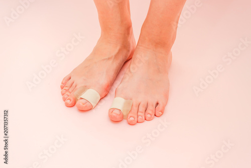 View on silicone finger separator. To treat and prevent of hallux valgus. Legs on a pink background.