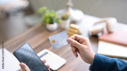 Konstfotografi Adult woman holding credit card while using smartphone for online payment at hom