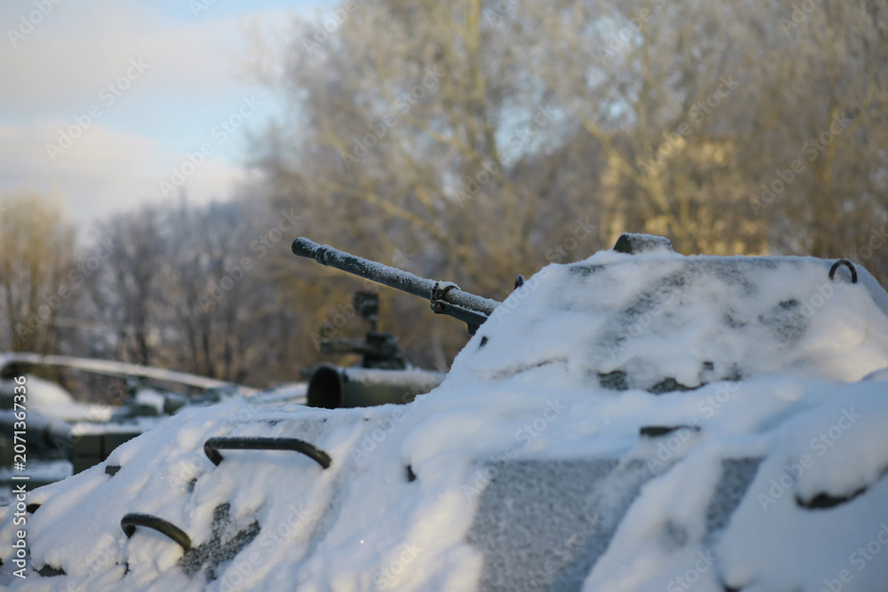Fototapeta premium Military tank in a row. Battle tank in the snow on the roadside of highway. War in Ukraine in winter.