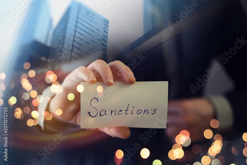 Slika na platnu Man showing sanctions word on paper and devastated middle aged caucasian man in