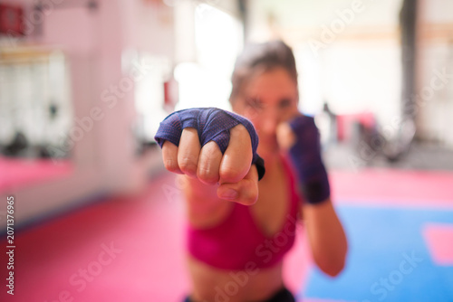 Fotografie Female athlete punching during kickboxing training in gym