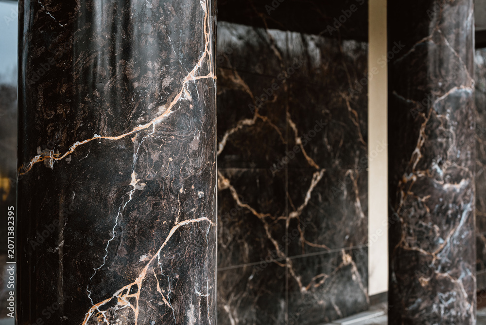 Naklejka premium Architectural detail of modern building entrance with blackmarble columns Elegant marble column detail inside luxury building entrance symbolizing wealth, status, and refined interior design