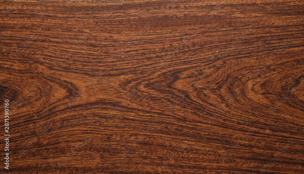 Fototapeta premium Rich dark wood texture featuring intricate grain patterns and flowing organic lines. Deep brown tones create a warm, elegant background with natural character and depth.