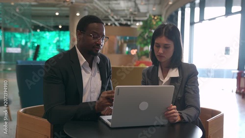Diverse business colleagues working together on a laptop in office