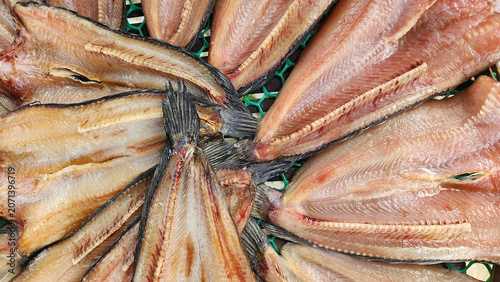 Canvas Print A top-down view of sun-dried striped snakehead fish split open and arranged in a circular pattern on a mesh tray at a traditional Thai market