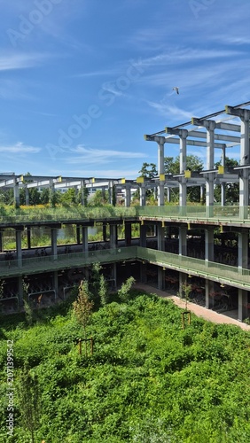 Canvastavla High angle view of a sustainable modern multilevel bike parking building integrated with extensive green roofs, lush plant corridors, and a flying bird