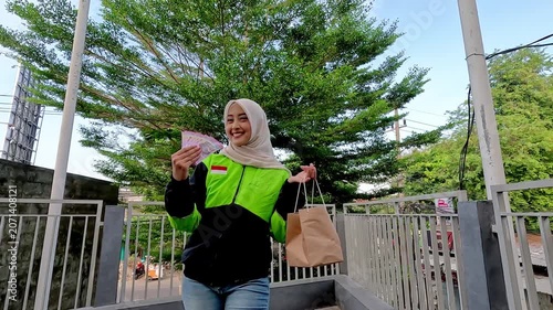A young Muslim Asian woman, an online motorcycle taxi driver, is doing her job.