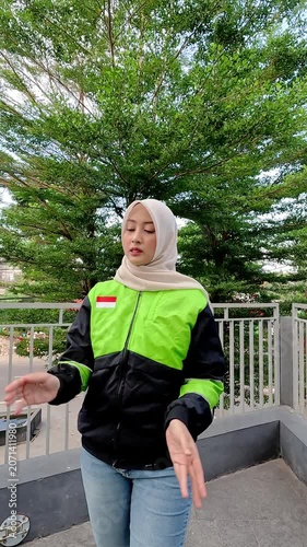 A young Muslim Asian woman, an online motorcycle taxi driver, is doing her job.