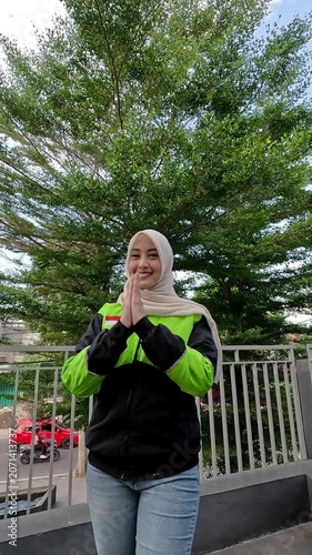 A young Muslim Asian woman, an online motorcycle taxi driver, is doing her job.