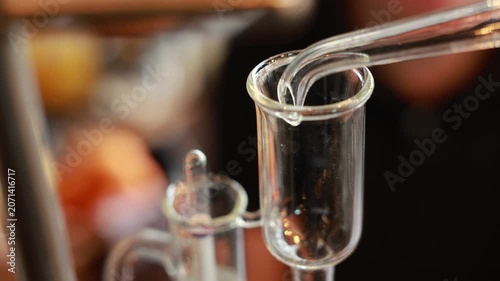 Gin distillation alcohol clear liquid pouring into glass vessel laboratory equipment close up transparent scientific process beverage production precise modern technique controlled environment