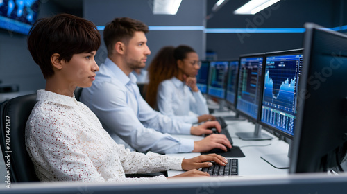 Financial analysts monitoring stock market data on multiple screens in trading office managing investments and market performance