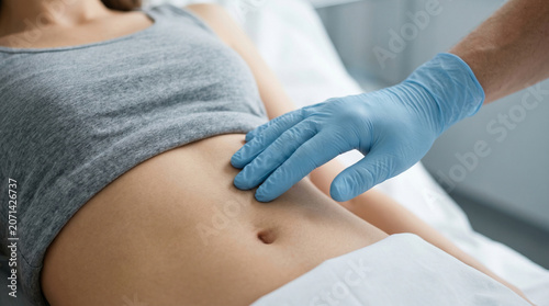 Close-up of a flat stomach of a young woman with a plastic surgeon's hand, minimalist concept of medical and aesthetic surgery