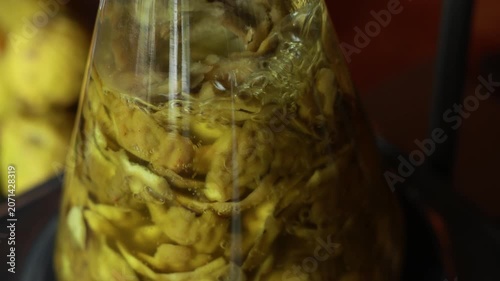 Herbal extraction glass flask liquid yellow organic natural closeup science laboratory hydrosol essential oil steam distillation process with yellow fruit slice and flower petal botanical extract