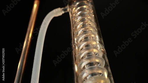 Glass coil condenser distillation equipment laboratory alcohol production gin distillation transparent spiral tube scientific closeup industrial process apparatus copper pipe chemistry modern