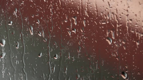 Rain water drop glass window wet condensation moisture transparent closeup with blurred background, soft lighting, natural texture, reflective surface, and moody calm atmosphere on window pane