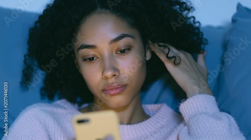 Gorgeous Black woman is reading an internet article. Late night online activity. Doomscrolling. Swiping profiles in dating app