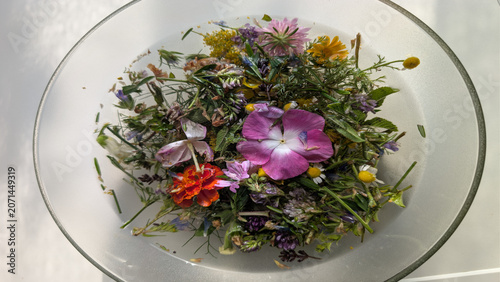 Erbe e fiori di San Giovanni immersi in acqua, disposti in una composizione naturale e colorata legata alle tradizioni del solstizio d’estate