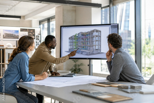 Diverse Bim Architecture Team Reviewing 3D Color Coded Model Large Screen Conference Table City View