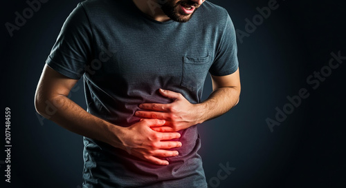 Young Caucasian man experiencing acute stomach pain, clutching his abdomen with a distressed express