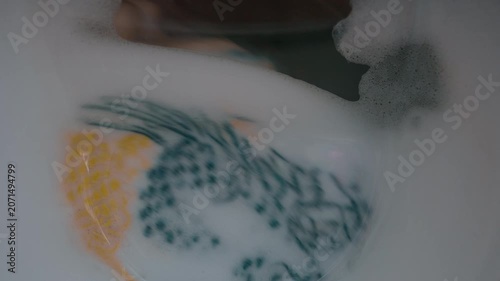 Clothing and soapy water spin around in machine. Washing machine door. Front loader