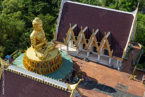 Canvas Print An aerial view of a golden Buddha statue and Wat Sam Phran temple complex surrounded by lush green trees in Bangkok, Thailand