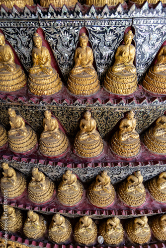 Fotografie Rows of golden Buddha statues adorn a temple wall in Wat Sam Phran, Bangkok, Thailand