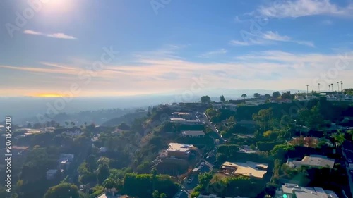 A panoramic view from the hill of the ocean, the sun, clouds, and eagles soaring in the sky.
