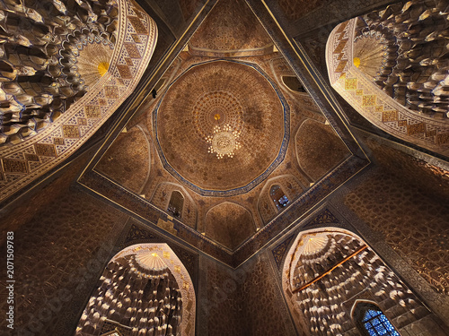 Ornate interior dome of Gur-e-Amir mausoleum in Samarkand featuring gilded muqarnas and geometric patterns. Ideal for travel publications, cultural heritage projects, and architectural studies.