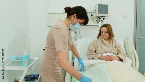 Doctor in sterile rubber gloves and protective mask folds clean medical napkin after examining patient. Physician completes examination. Slow motion