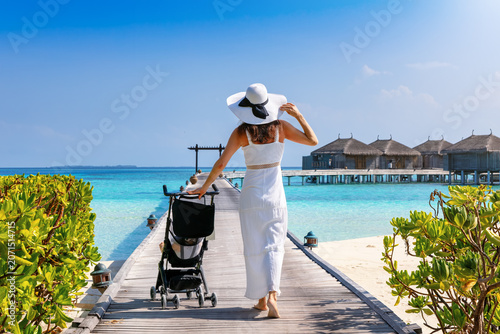 Fotografia A elegant woman in a white dress walks over a pier in the Maldives islands pushi