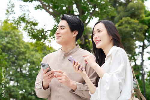 Foto 公園でスマホを持って話す笑顔のカップル30代