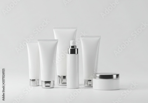 Minimalist white cosmetic tubes and jar with silver accents on a white background