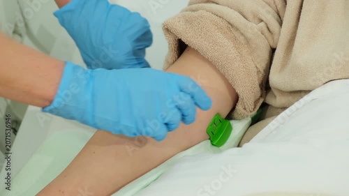 Attentive doctor secures and tightens tourniquet around arm of patient. Physician prepares for safe catheter insertion procedure. Slow motion