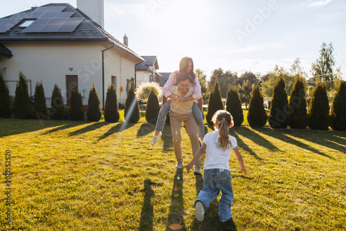 Photos Happy family playing together in backyard with solar panels