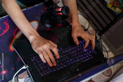 Slika na platnu Two hands type quickly on a backlit gaming laptop keyboard with colorful rgb lig
