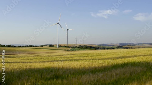 Wind turbines on farmland during sunny day with blue sky