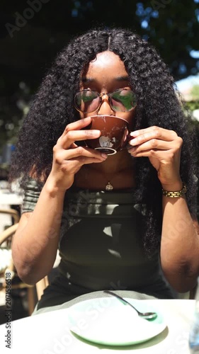 Young woman drinking and enjoying coffee in a cafe outdoors