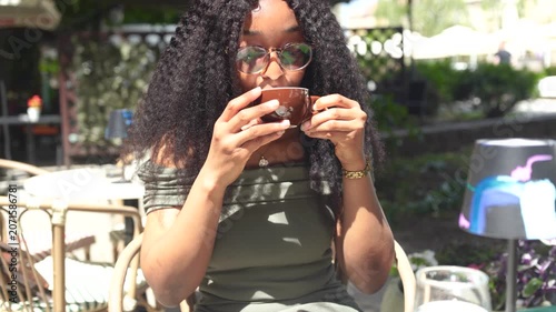Young woman drinking and enjoying coffee in a cafe outdoors