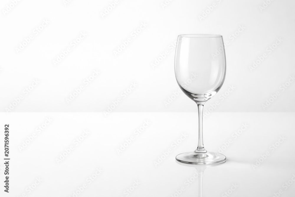 Fototapeta premium Clear glass wine glass with a slender stem and wide bowl, positioned on a light background, showcasing its elegant design and transparency
