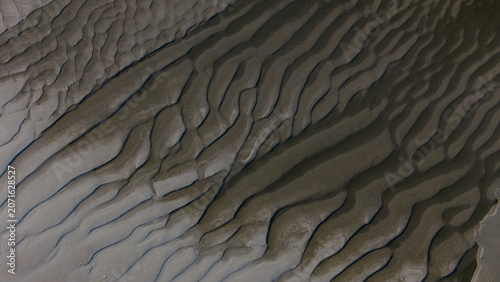Close-up aerial view of undulating sand dunes with natural wave-like formations, showcasing textures and shadows