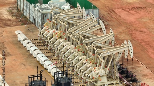 фотографія Aerial drone view of multiple oil pumpjacks aligned in a vast dry field, showcasing large-scale petroleum extraction, industrial energy production, and the backbone of global oil supply systems
