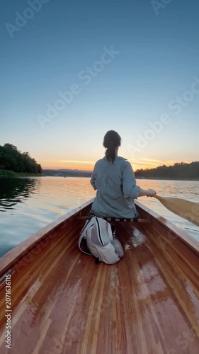 Woman paddling canoe at sunset
