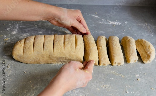Fotografie Hands dividing raw pastry dough into equal portions on a counter.