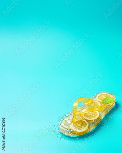 Lemon slice flip flop with water droplets on turquoise background, summer drink advertising background