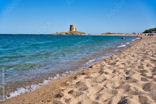 Sandy beach bay an ancient coastal watchtower on a rocky outcrop in Torre di Bari, Sardinia.