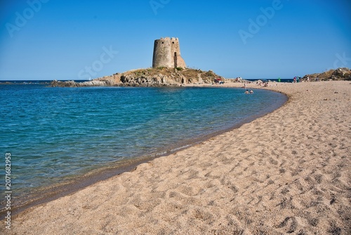 Sandy beach bay an ancient coastal watchtower on a rocky outcrop in Torre di Bari, Sardinia.